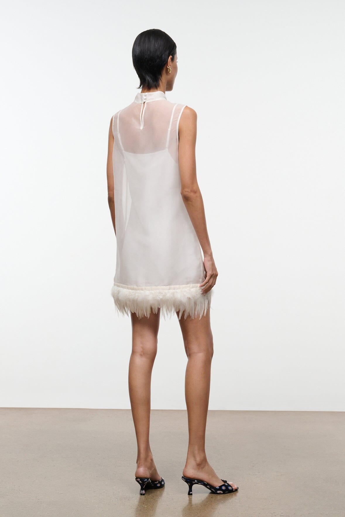 Ivory back view mini dress with sleeveless design and feather fringe hem