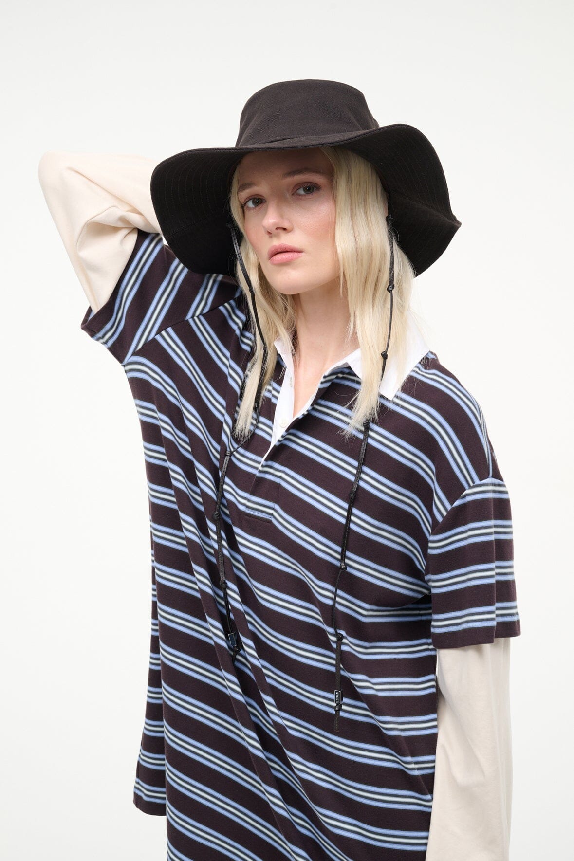 Dark brown bucket hat on model, wide brim with chin strap cords