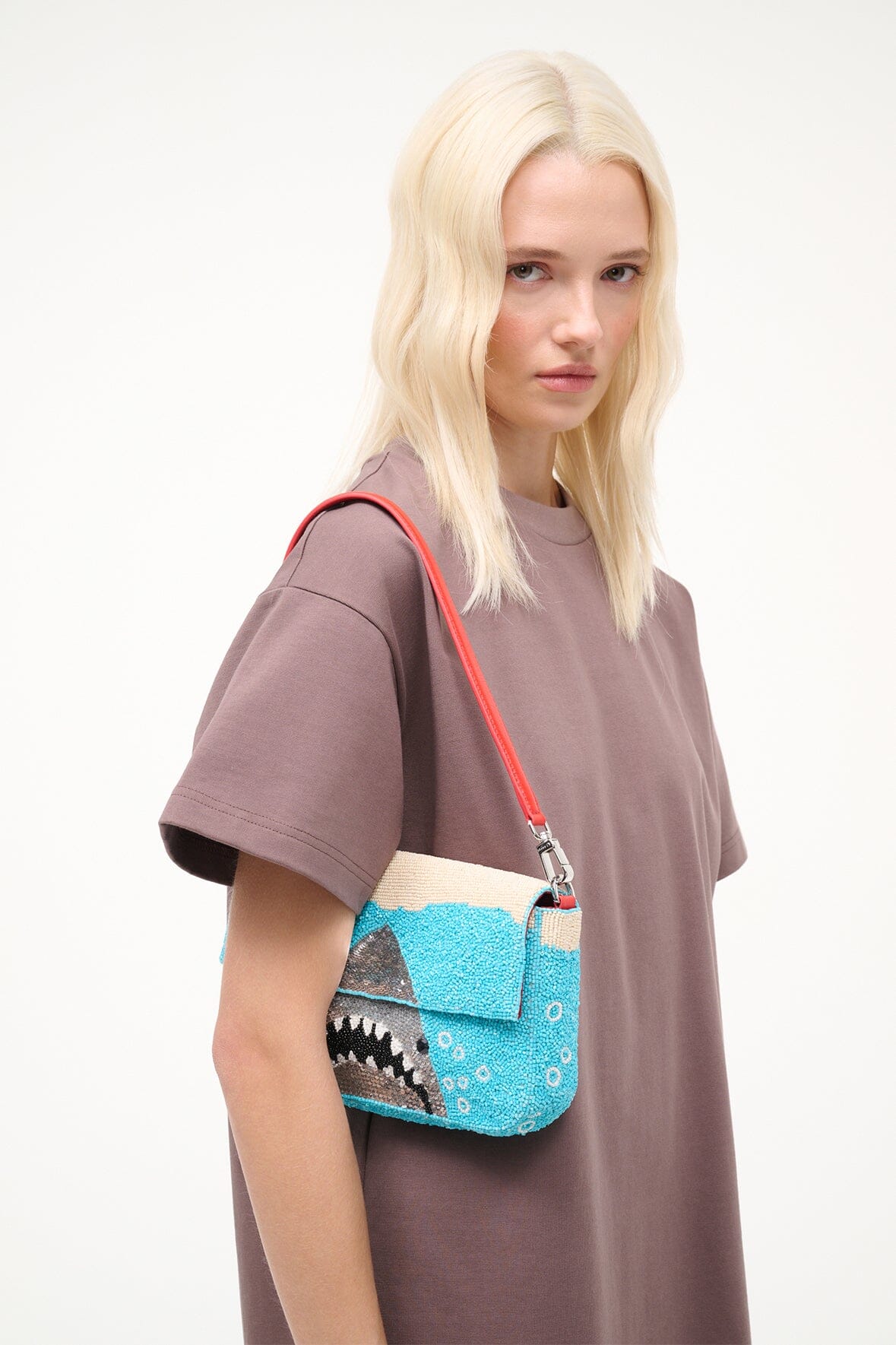 Turquoise sequin shoulder bag worn on shoulder with red strap and shark design.