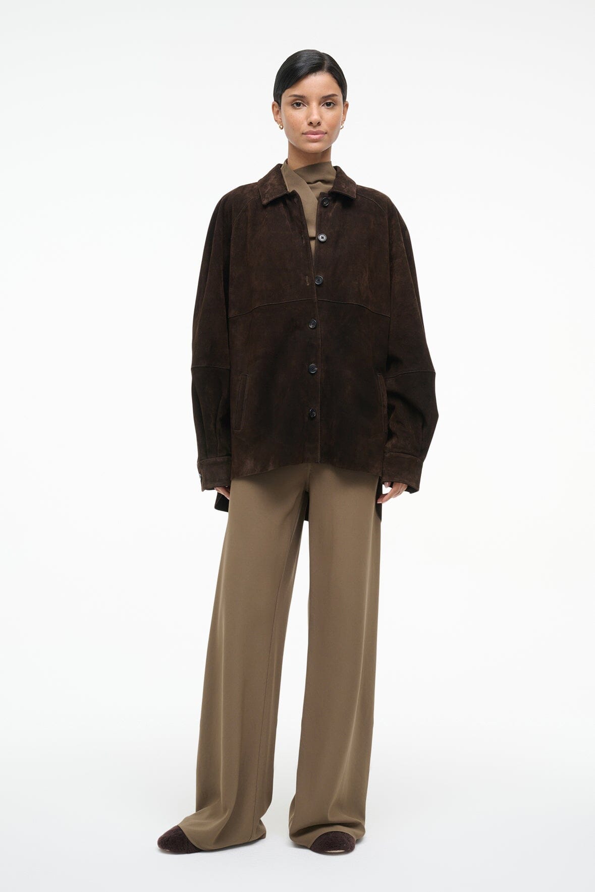 Dark brown suede button-up shirt with pointed collar and flap pocket, worn with beige trousers.