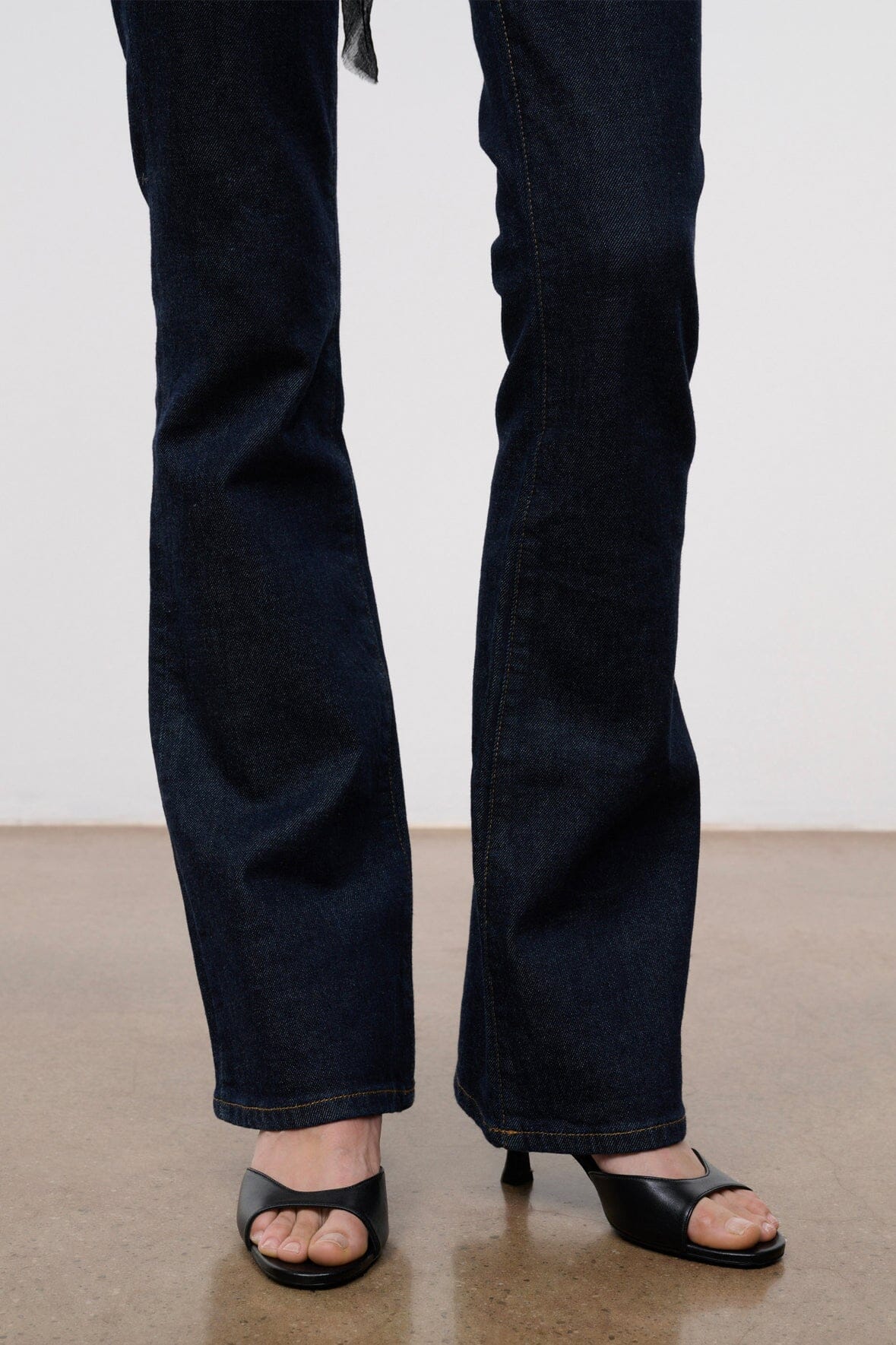 Indigo stretch flare jeans showing straight legs and flared hems with black sandals