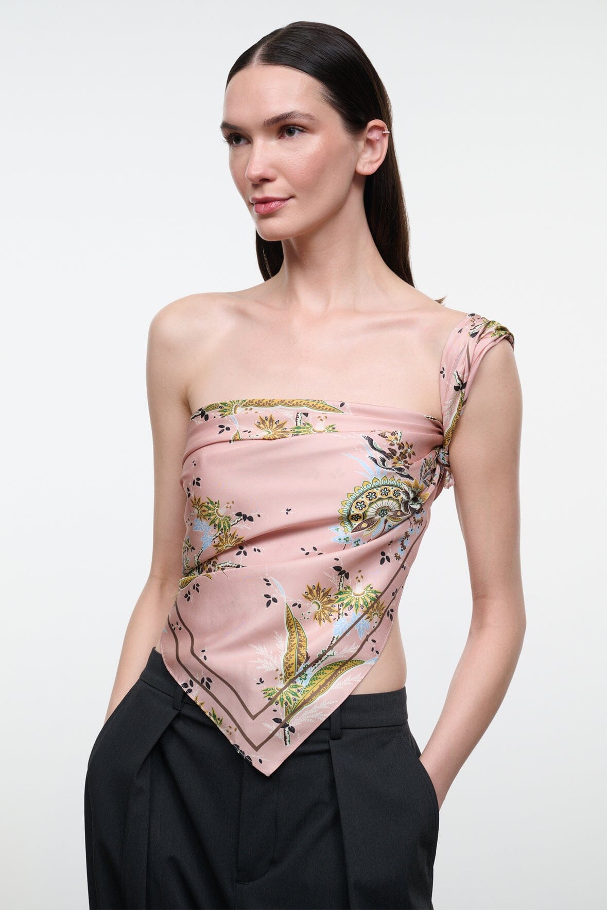Silk scarf draped as one-shoulder top in pink floral paisley print with gold and green motifs.