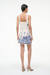 Back view of sleeveless blue toile shift dress with open-back cutout and tassel-trim hem