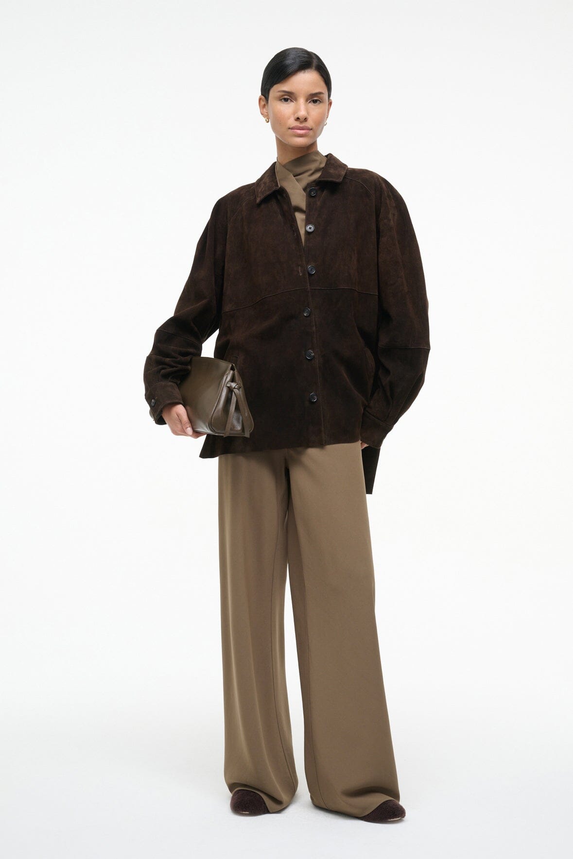 Truffle-brown soft clutch with top zipper, carried in hand