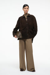 Truffle-brown soft clutch with top zipper, carried in hand