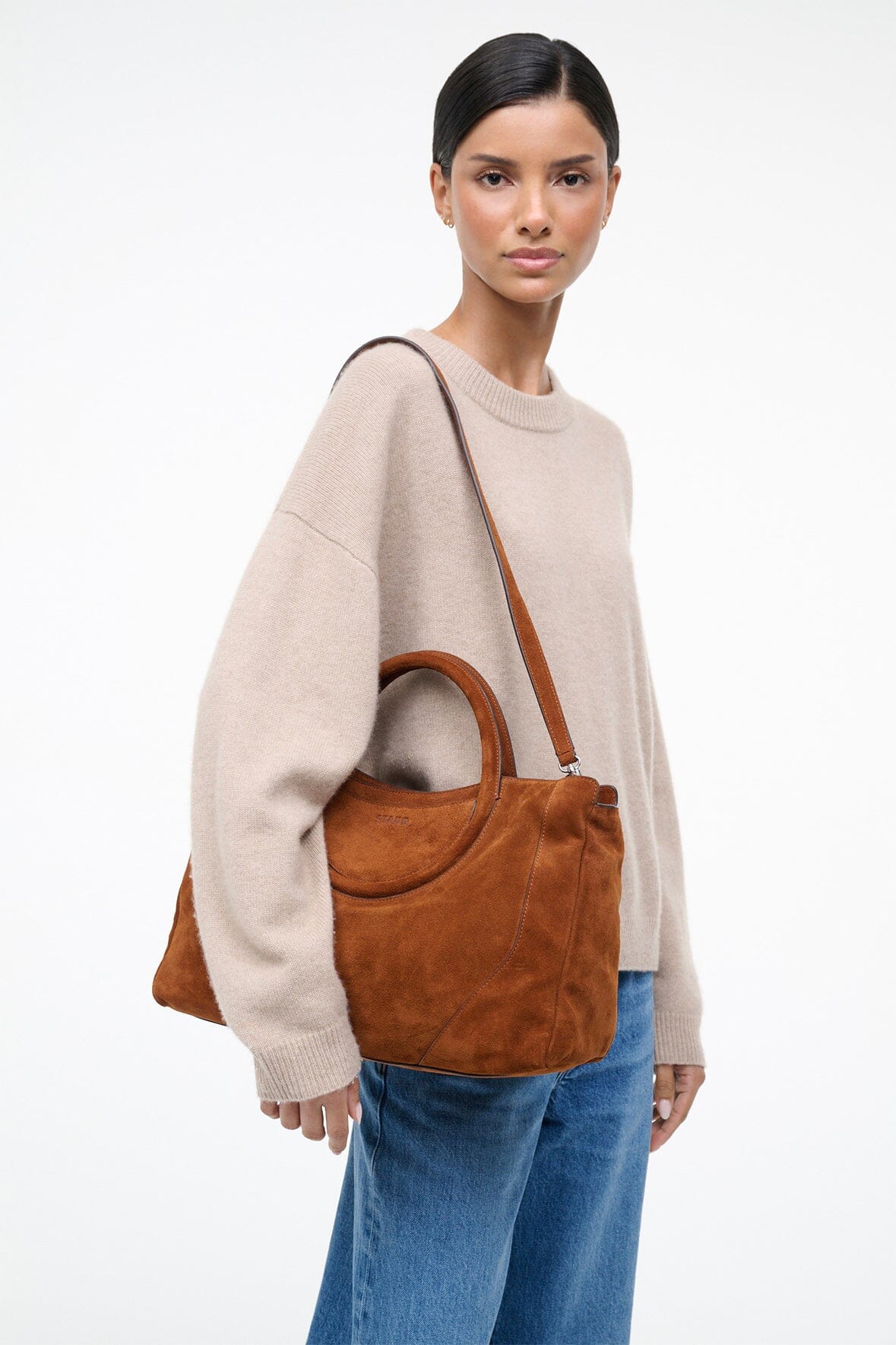 Tan suede satchel with top handle and shoulder strap, curved front panel, roomy body