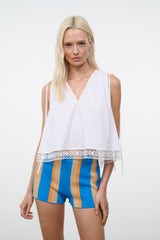 White sleeveless V-neck top with lace panel hem and loose fit