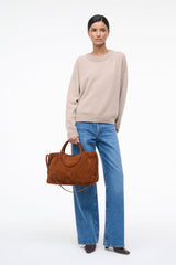 Brown suede satchel with top handles and detachable shoulder strap, curved pocket front