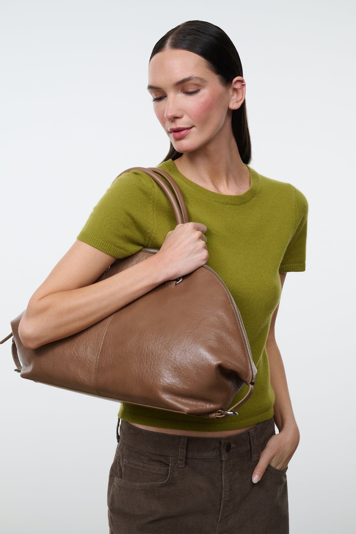 Brown leather satchel bag with top handles and zip closure, side view