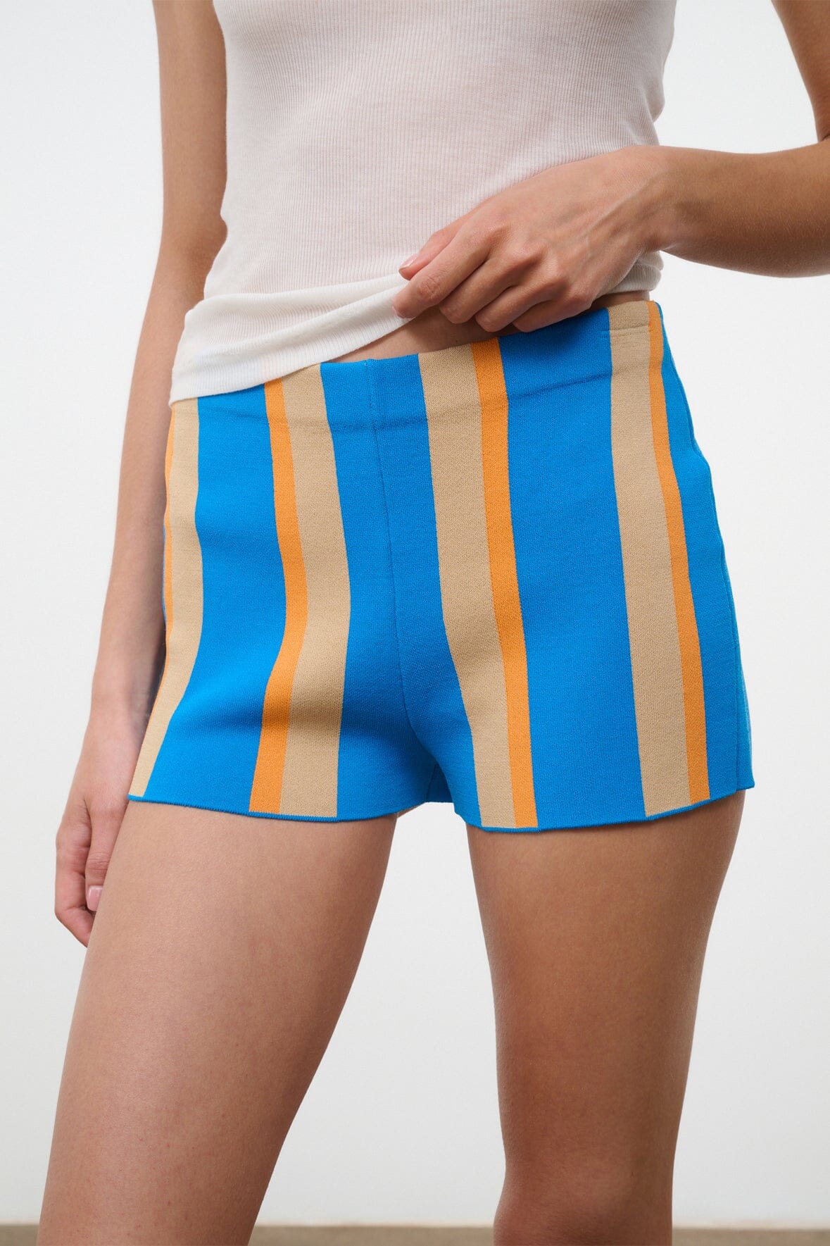 Close-up of blue striped shorts with vertical orange and beige panels, side seam
