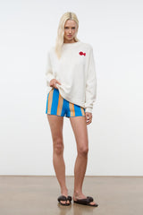 Blue striped shorts with vertical orange and beige stripes, mid-thigh length on model