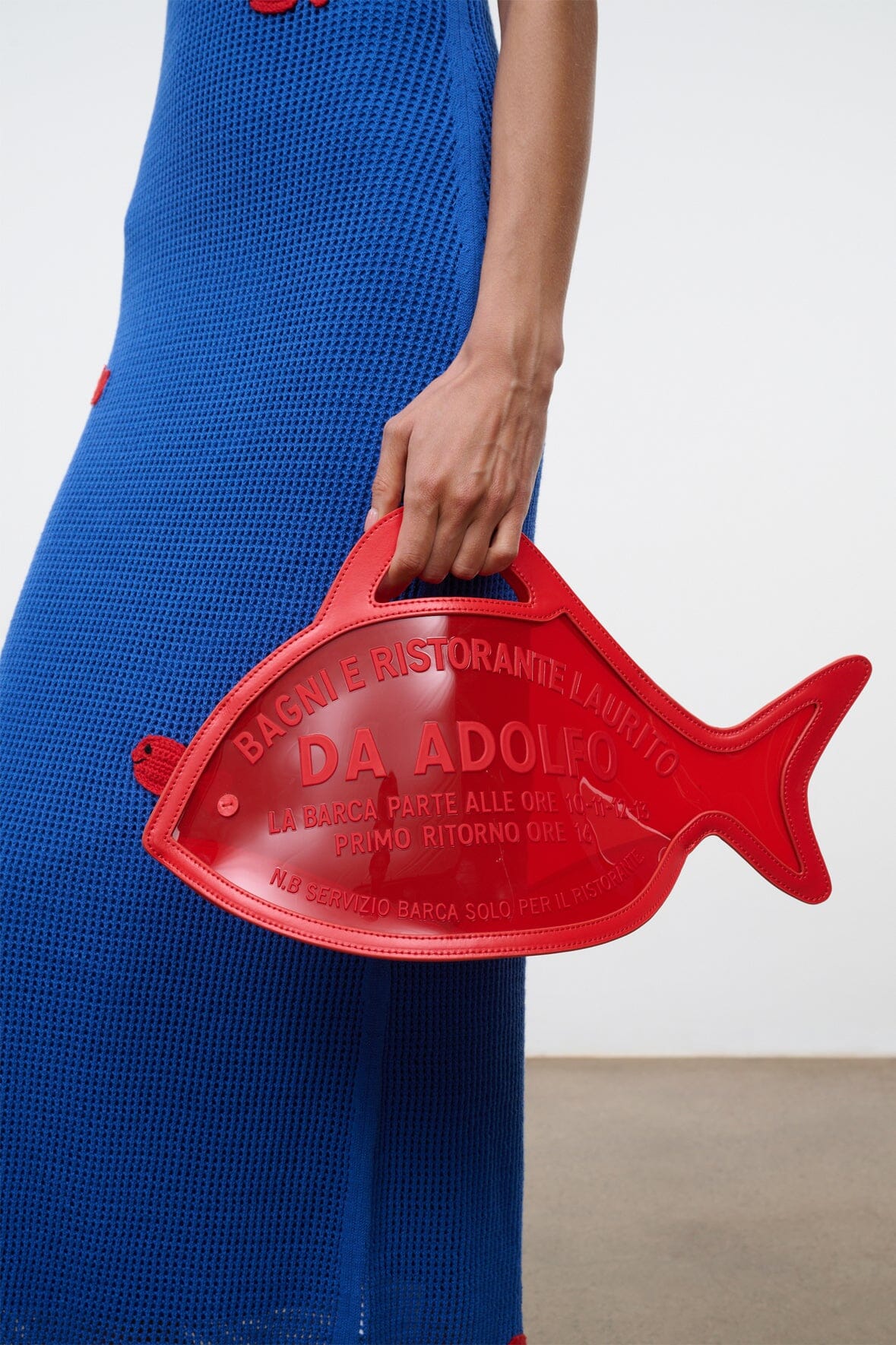 Red fish bag with handle, held in front with printed logo text panel