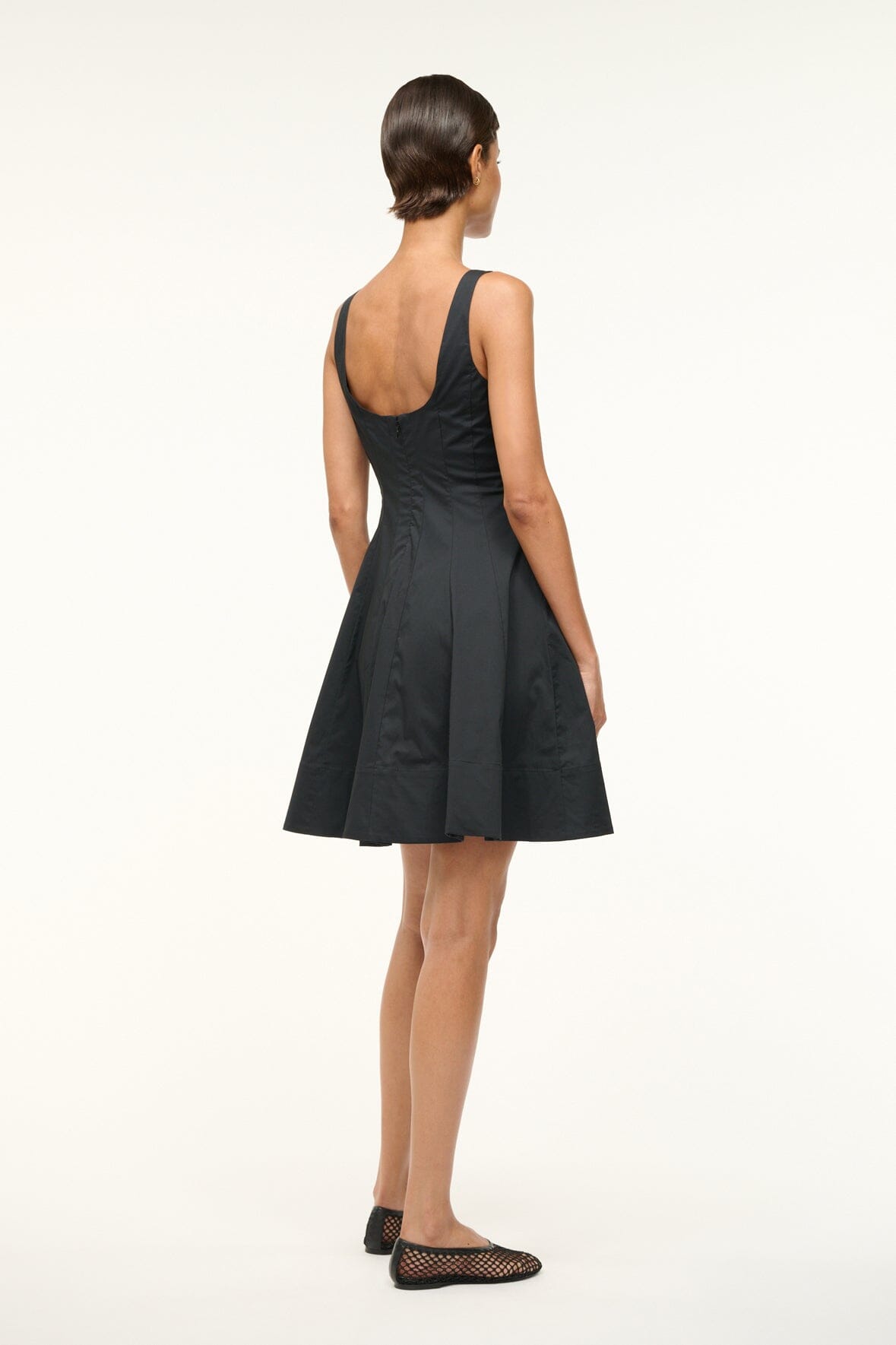 Black sleeveless mini dress back view with open scoop back and pleated skirt