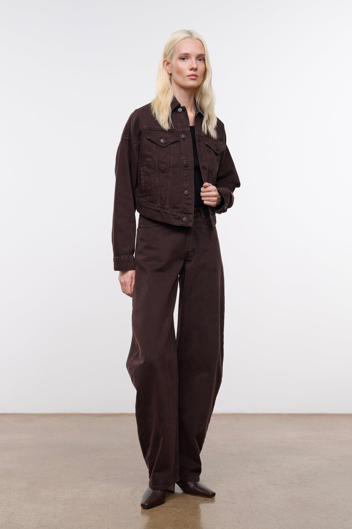 Dark brown denim jacket with button front and flap chest pockets, side view