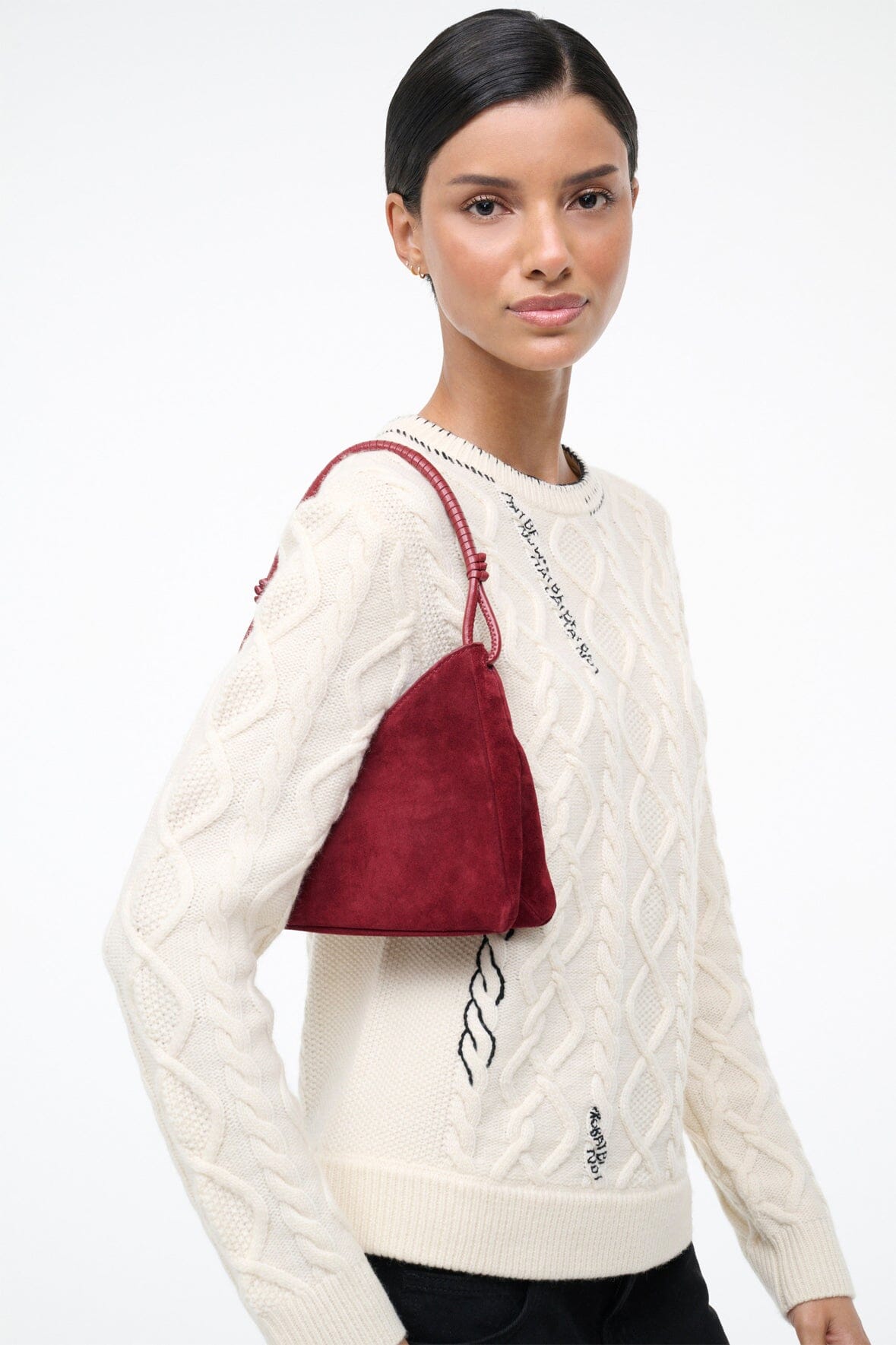 Burgundy suede shoulder bag worn on shoulder with small size and texture