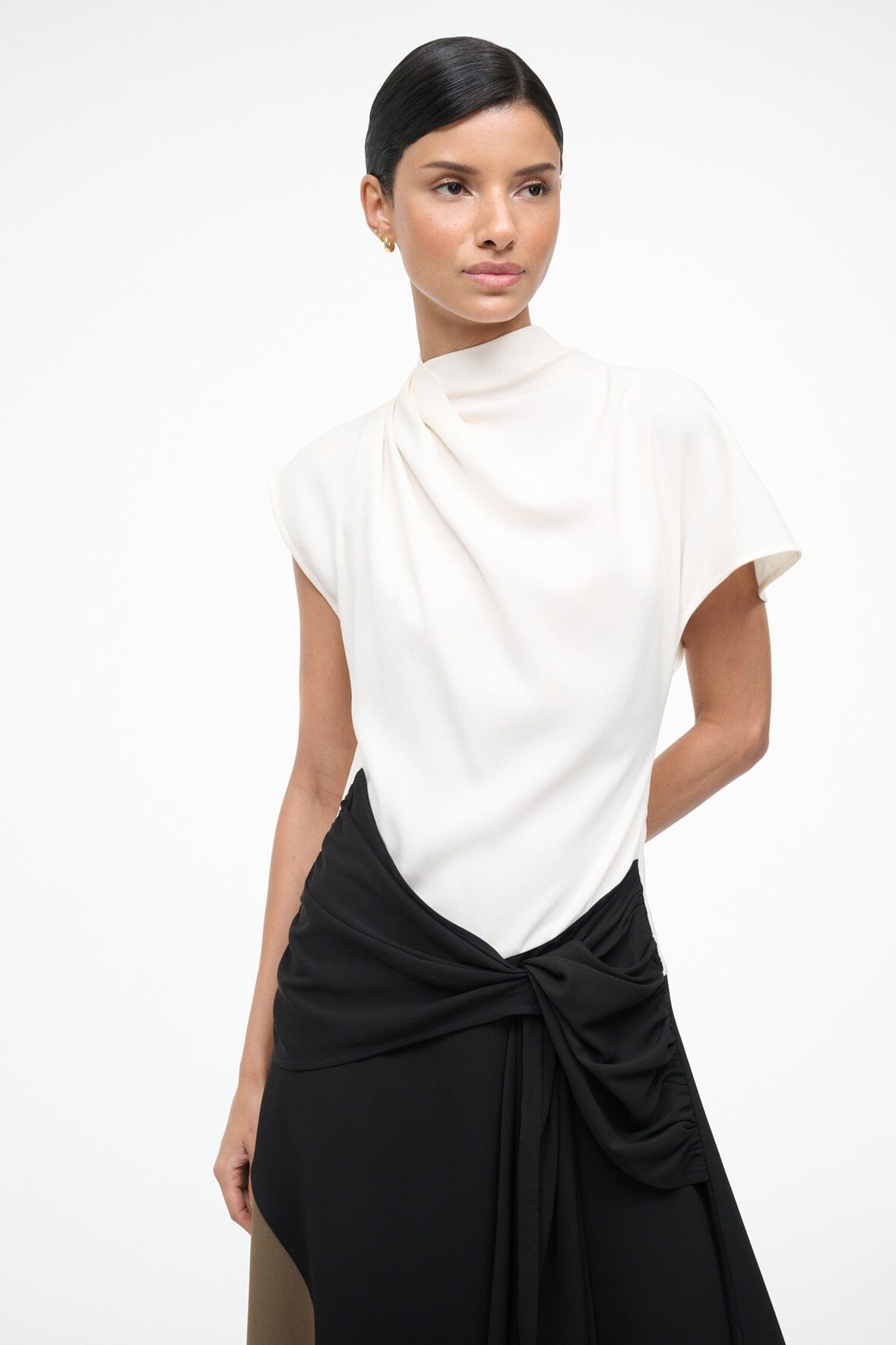 Sleeveless high-neck dress with white upper, black bow-tied waist and draped skirt