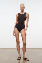 Black studded one-piece swimsuit on model, sleeveless with high-cut legs