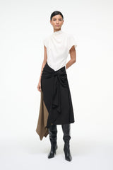 Sleeveless high-neck dress, front view, white top with black wrap knot and tan side panel