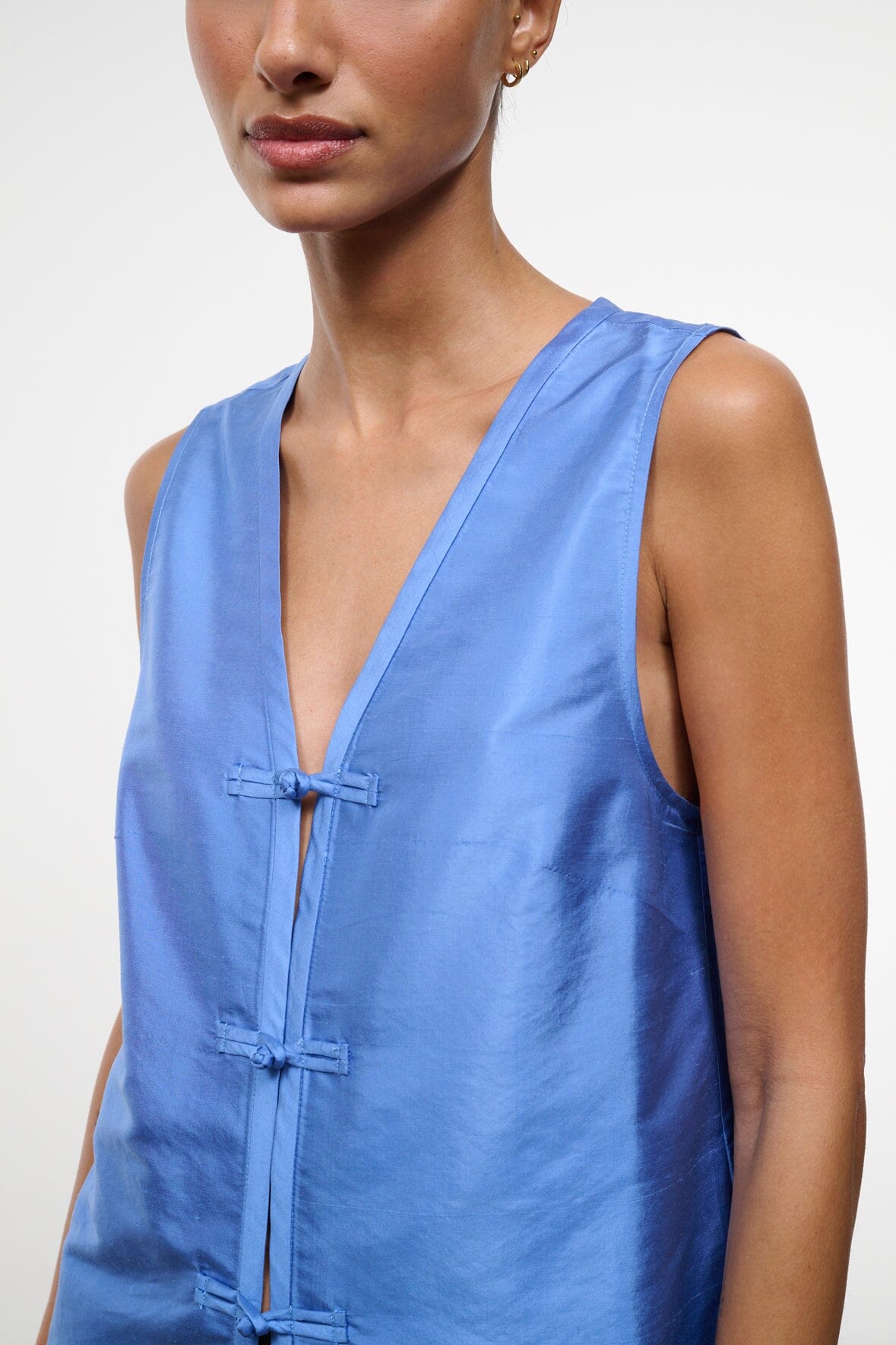 Light blue silk dupioni sleeveless top with V-neck and frog button placket