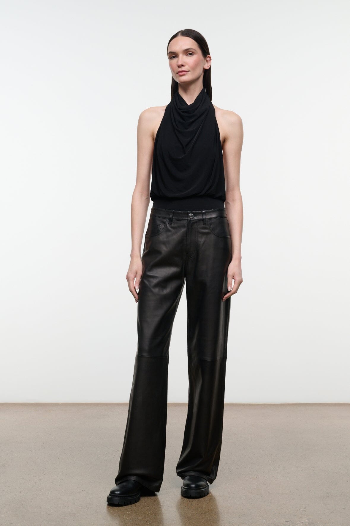 Black leather pants with high rise, belt loops, and wide straight-leg silhouette