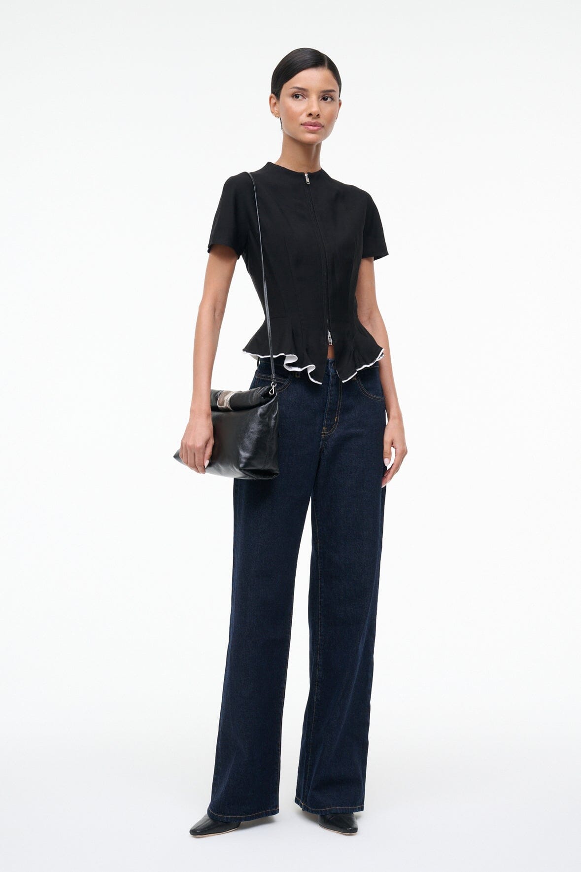 Black leather cuff clutch bag with silver-tone clasp and wrist strap, held by model