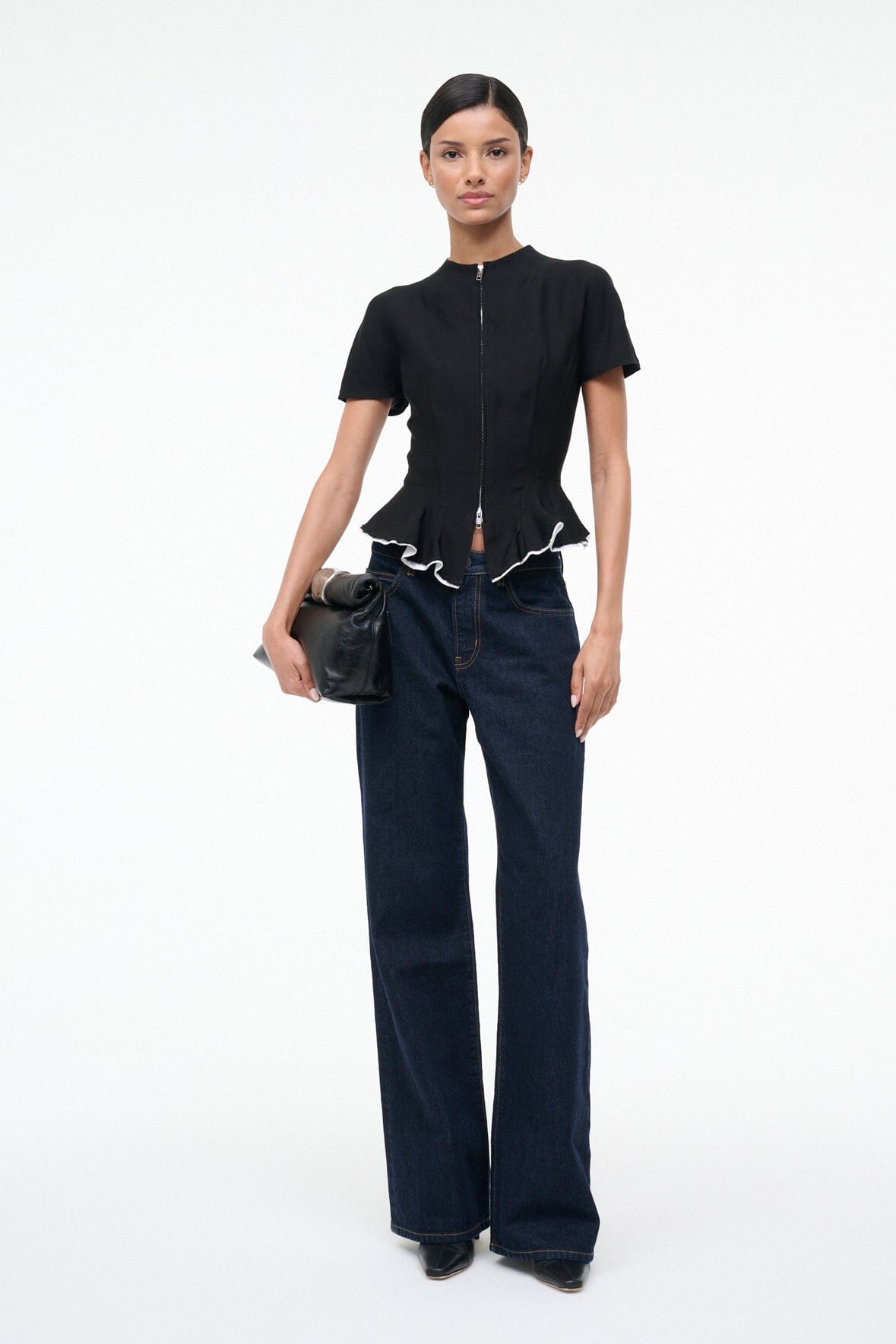 Black leather cuff clutch bag with folded top flap, carried at side with wrist strap