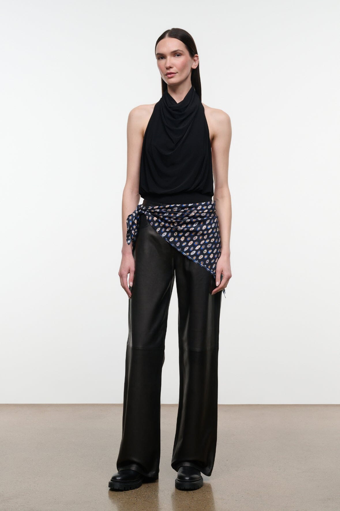 Black leather trousers with wide legs, front pockets, and subtle stitched paneling