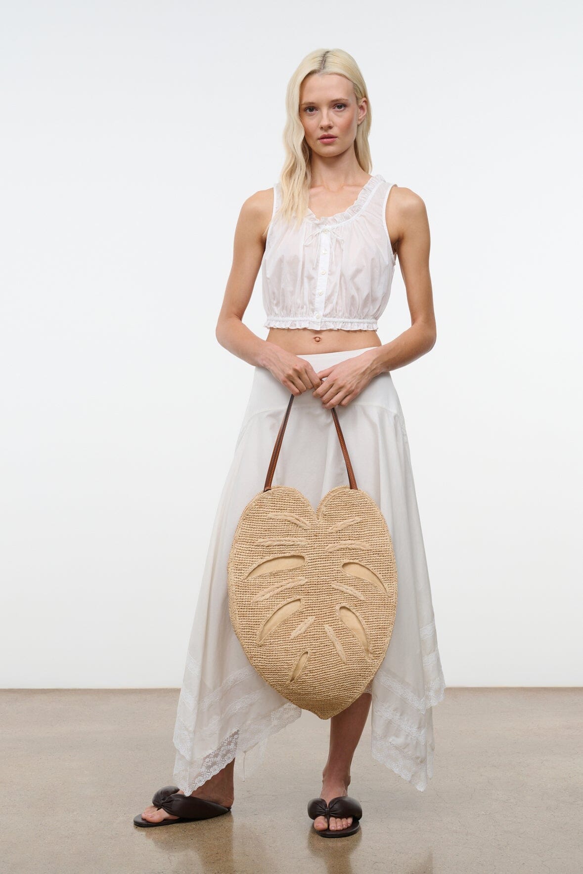 Natural raffia palm leaf bag on-model with brown leather handles, large round shape
