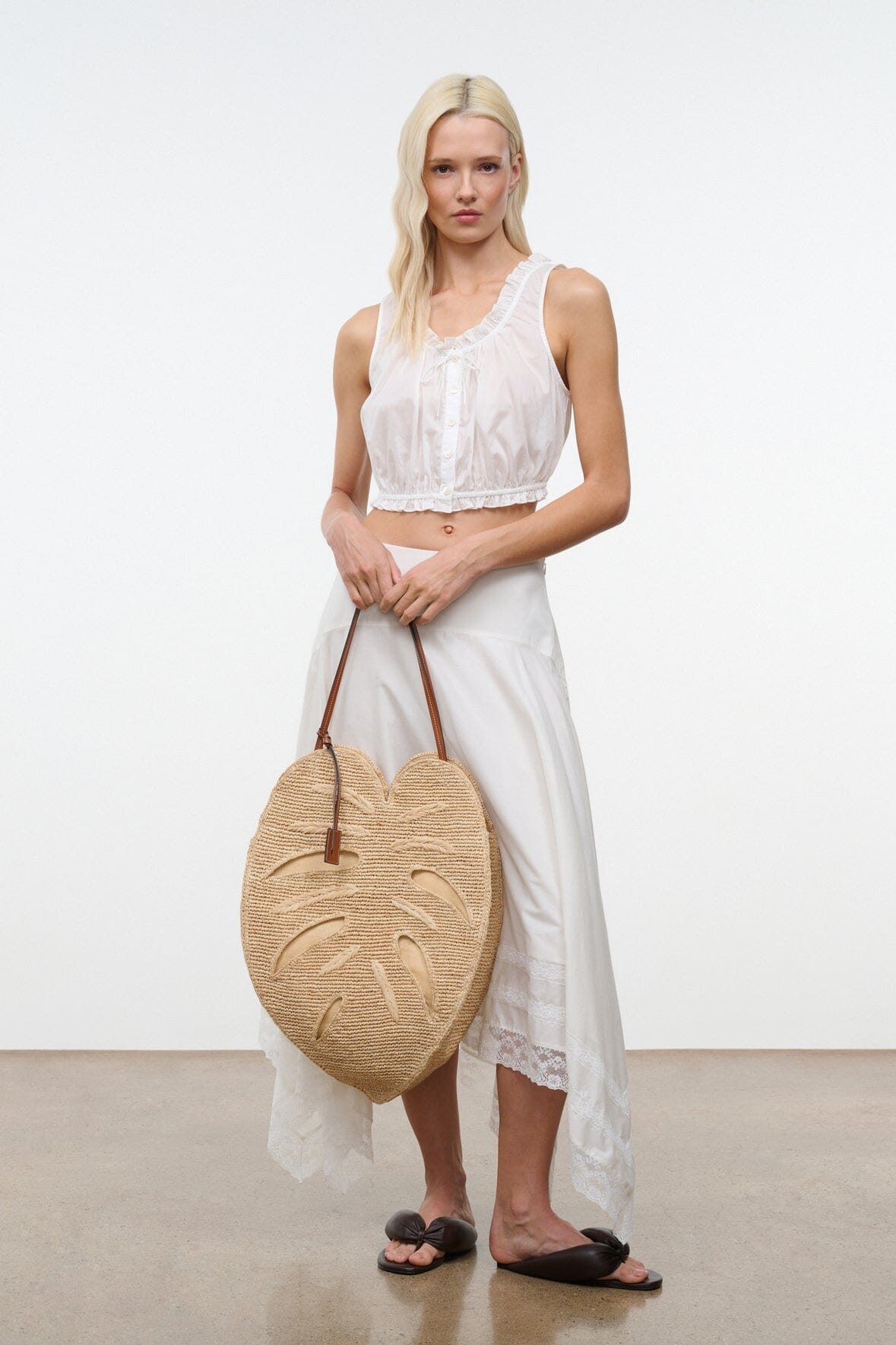 Natural raffia palm leaf tote bag on-model with brown leather handles and leaf front