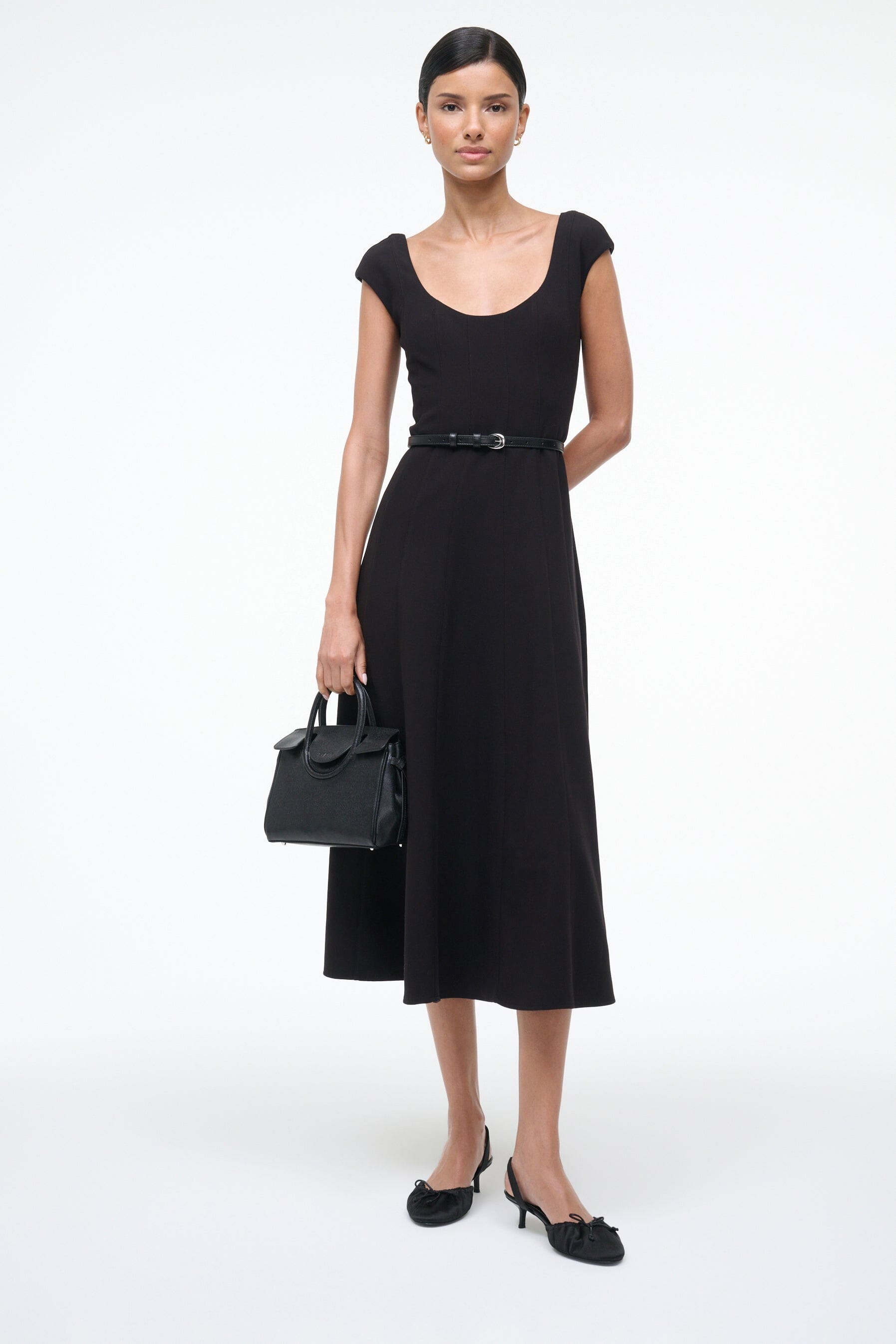 Black satin slingback ballet shoes with bow and low heel, worn with a dress