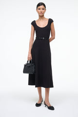 Black satin slingback ballet shoes with bow and low heel, worn with a dress