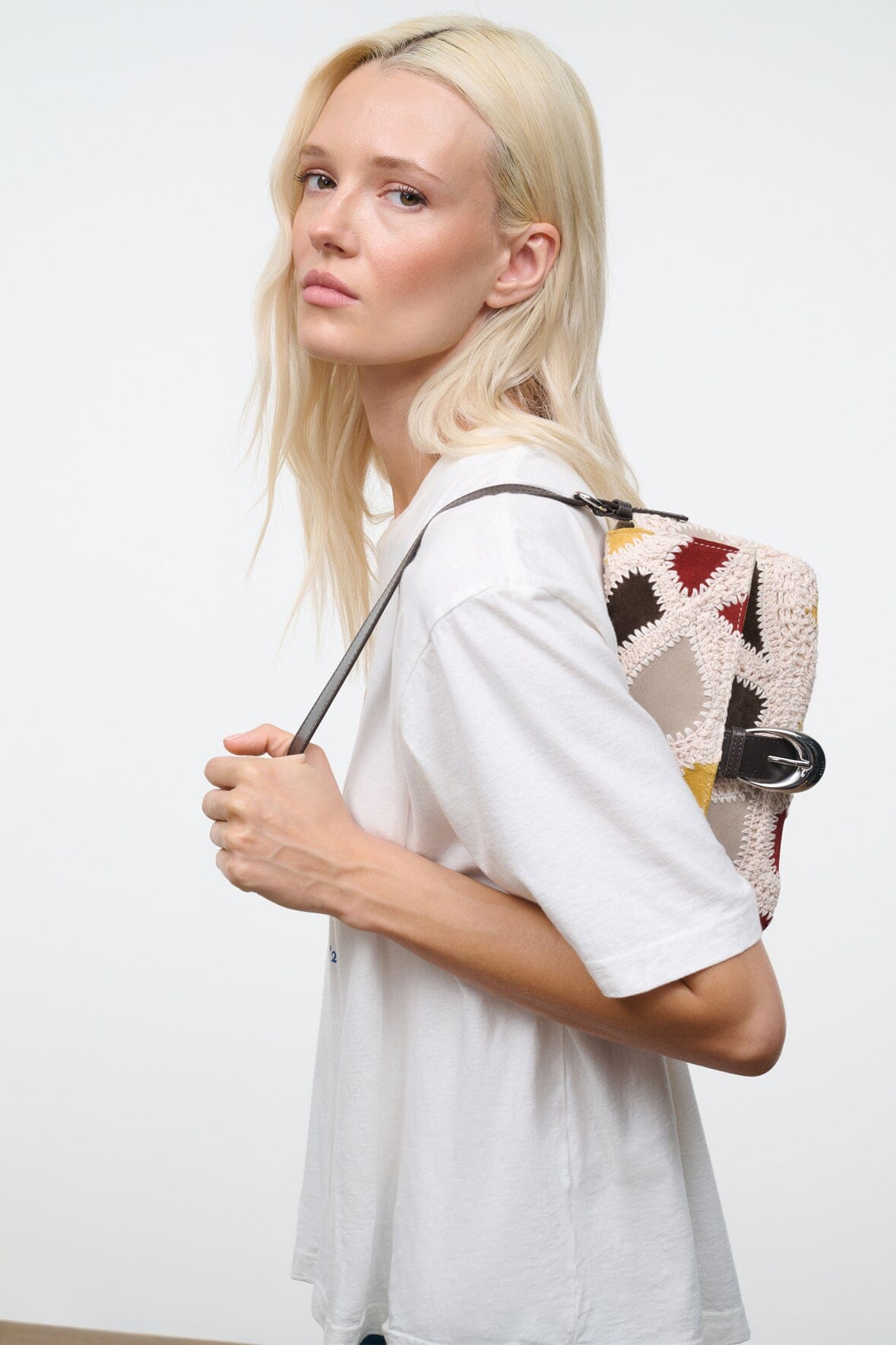 Patchwork suede bag with patterned front panel and metal clasp at the handle