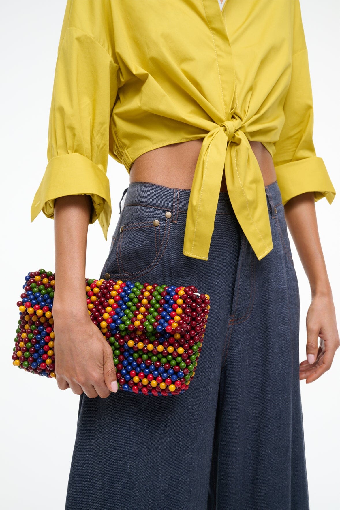 Multicolor beaded shoulder bag held at side with brown strap
