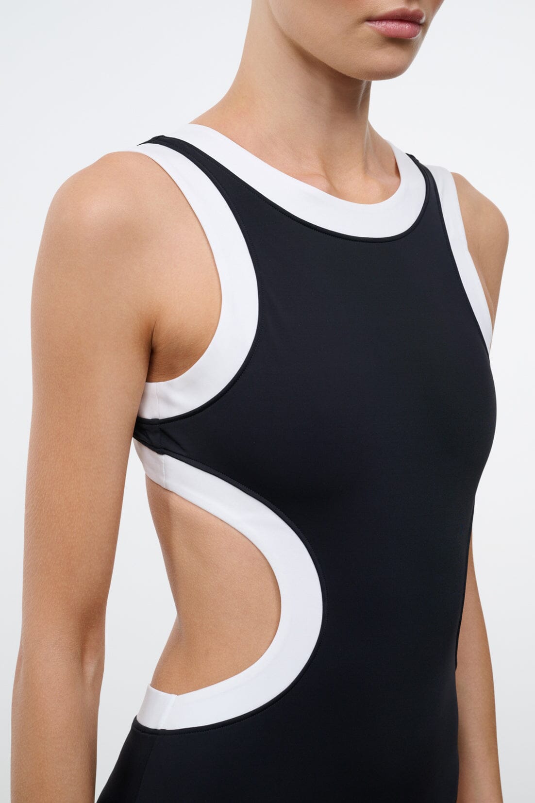 Black one-piece swimsuit with white-trimmed neckline and side cutouts outlined in white