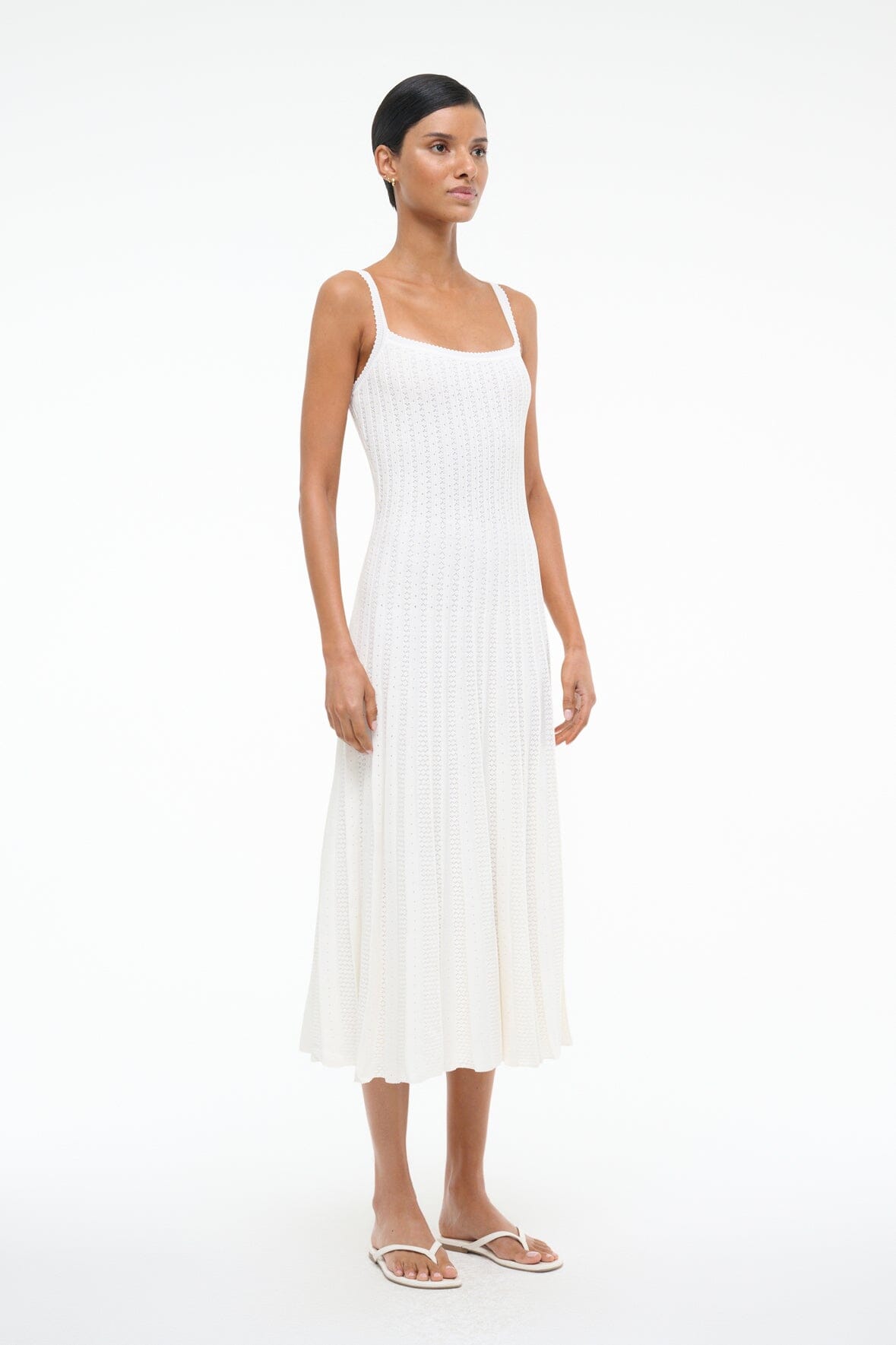 White crisscross-strap thong sandals with flat sole, worn by model