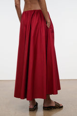 Red pleated midi skirt with gathered waistband, draping from hip