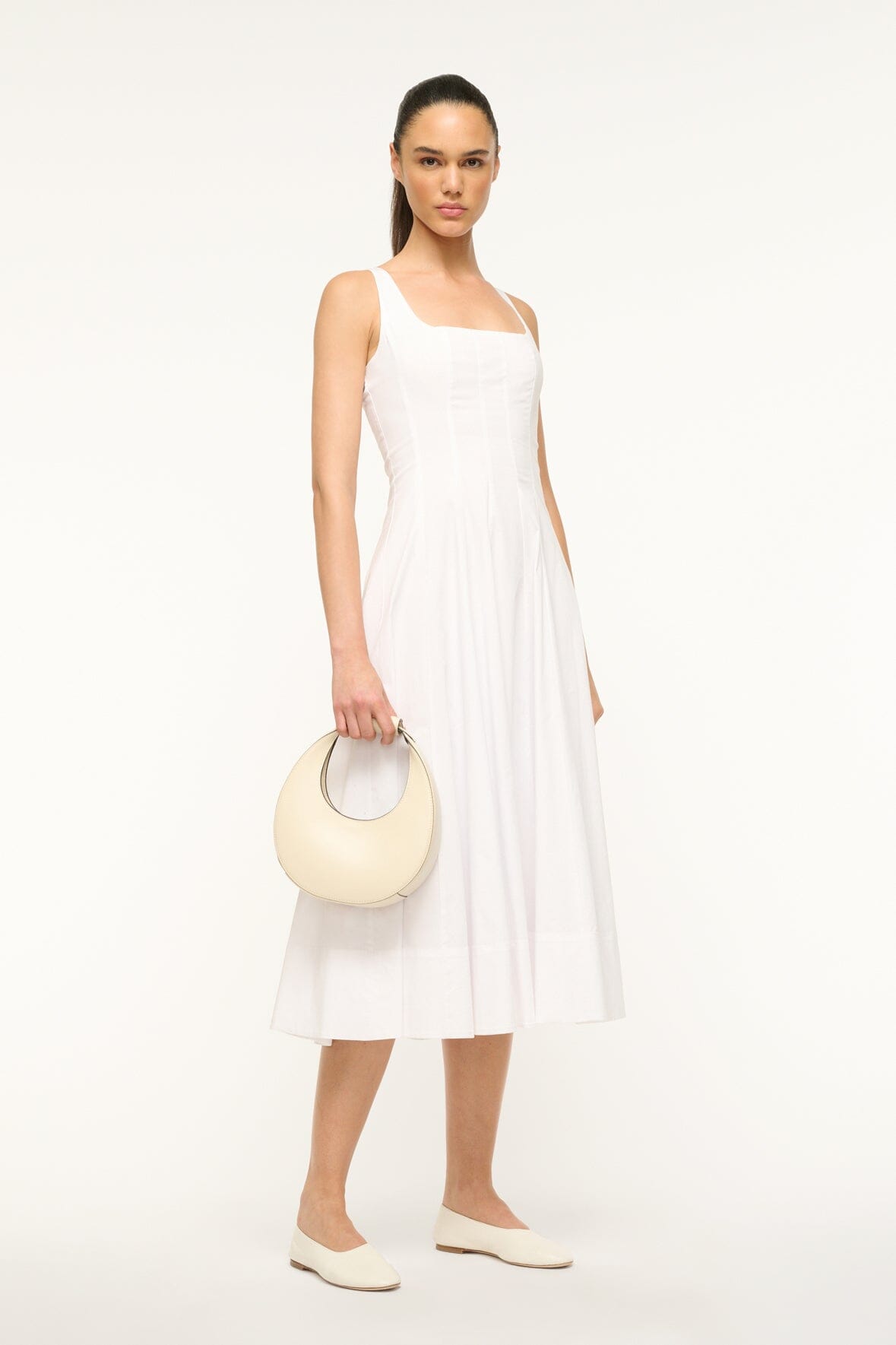 Cream mini moon bag carried at side with top handle