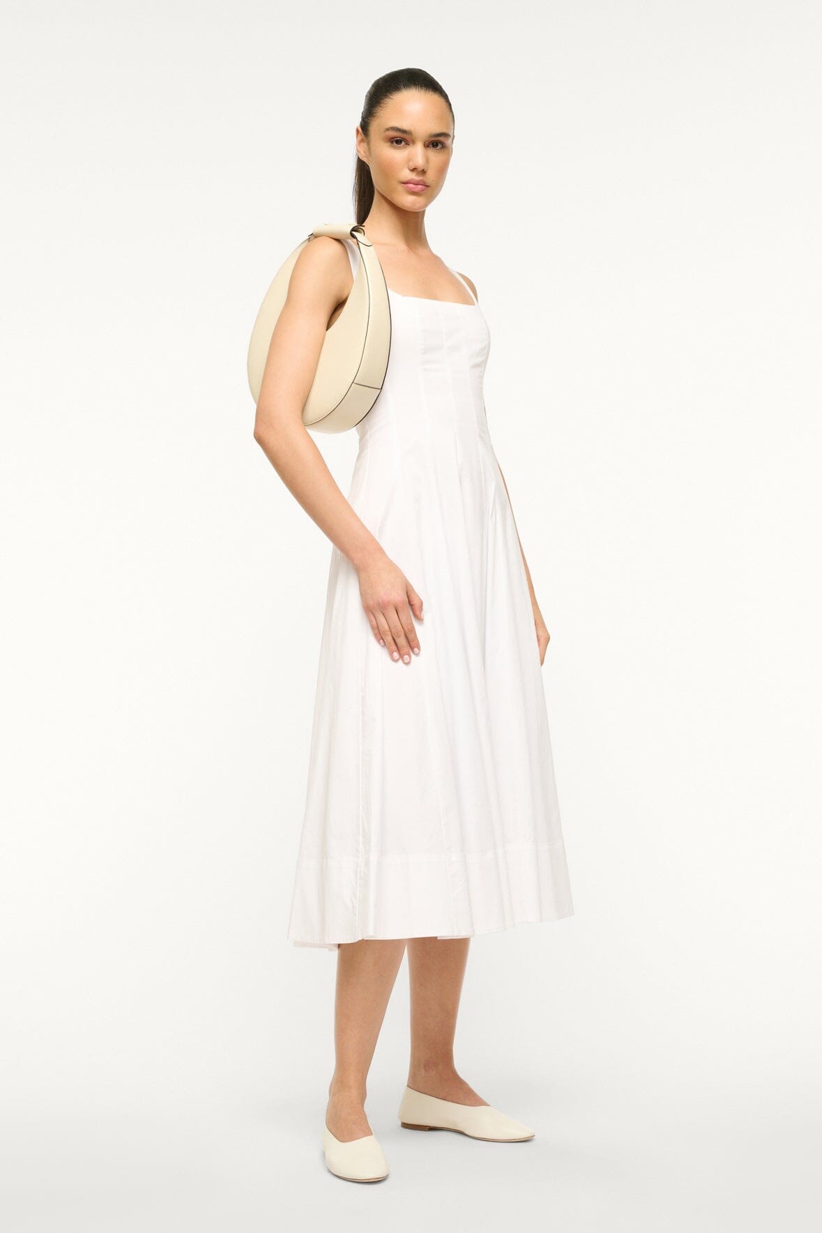 Cream crescent moon bag worn over the shoulder with top handle