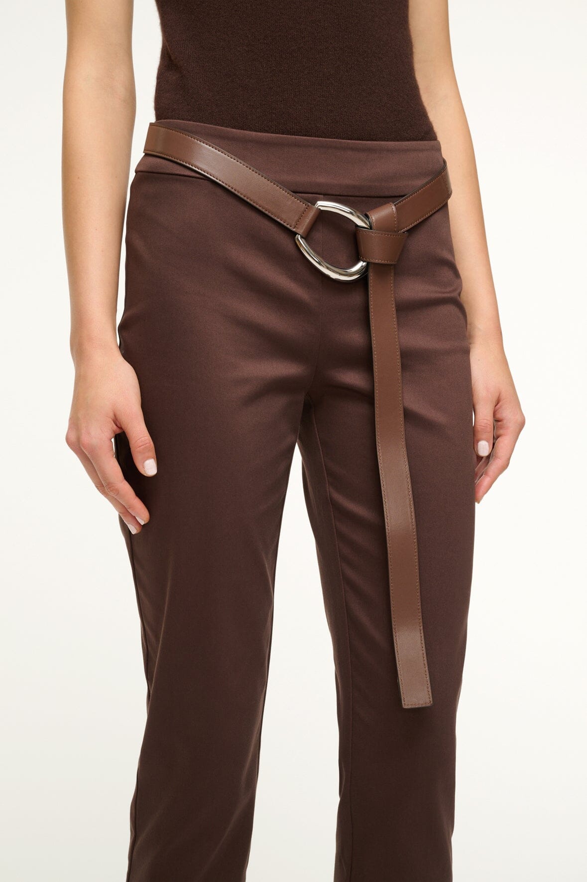 Mahogany brown wrap belt at waist with silver oval buckle on dark trousers