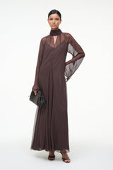 Brown maxi dress with high neck scarf, sheer sleeves, and side drape detail