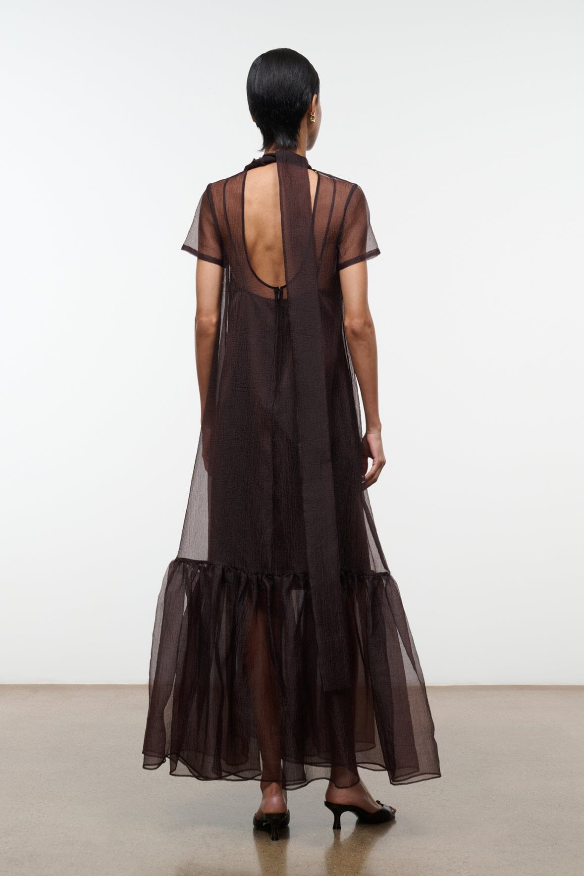 Dark brown sheer maxi dress with open back and vertical draped mesh panel