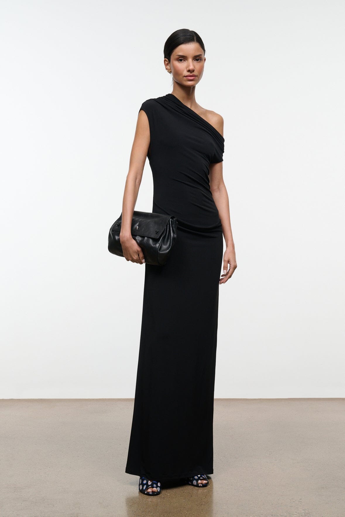 Black convertible shoulder bag with flap and small front logo, carried across the body