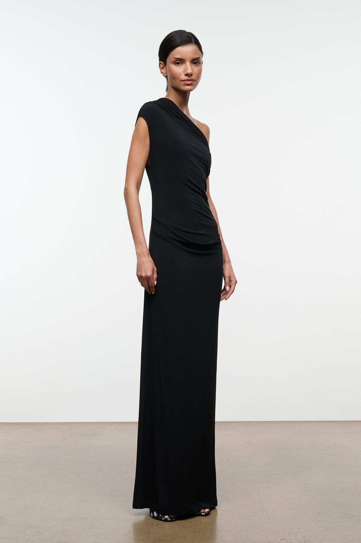 Black one-shoulder draped maxi dress, sleeveless, angled front view