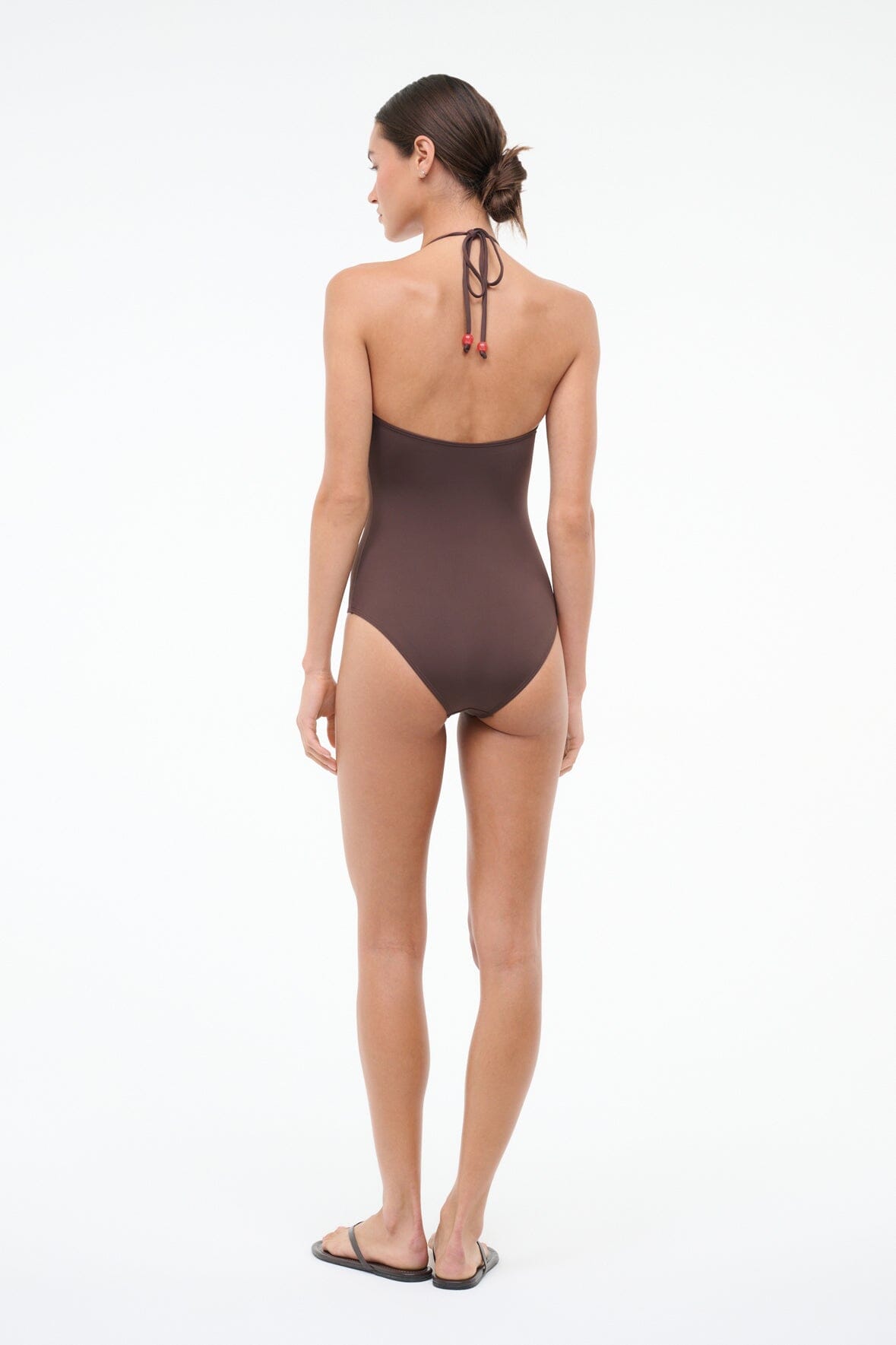 Back view of dark brown halter one-piece with tie-back and red beaded accents