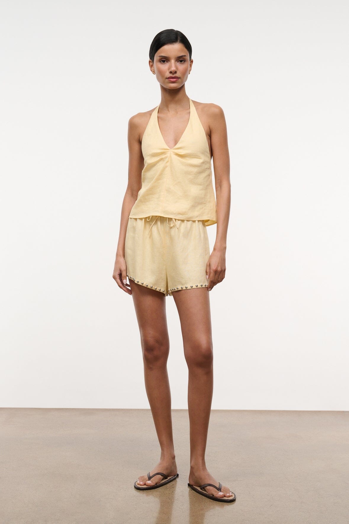 Butter linen halter top with V neckline and gathered peplum hem