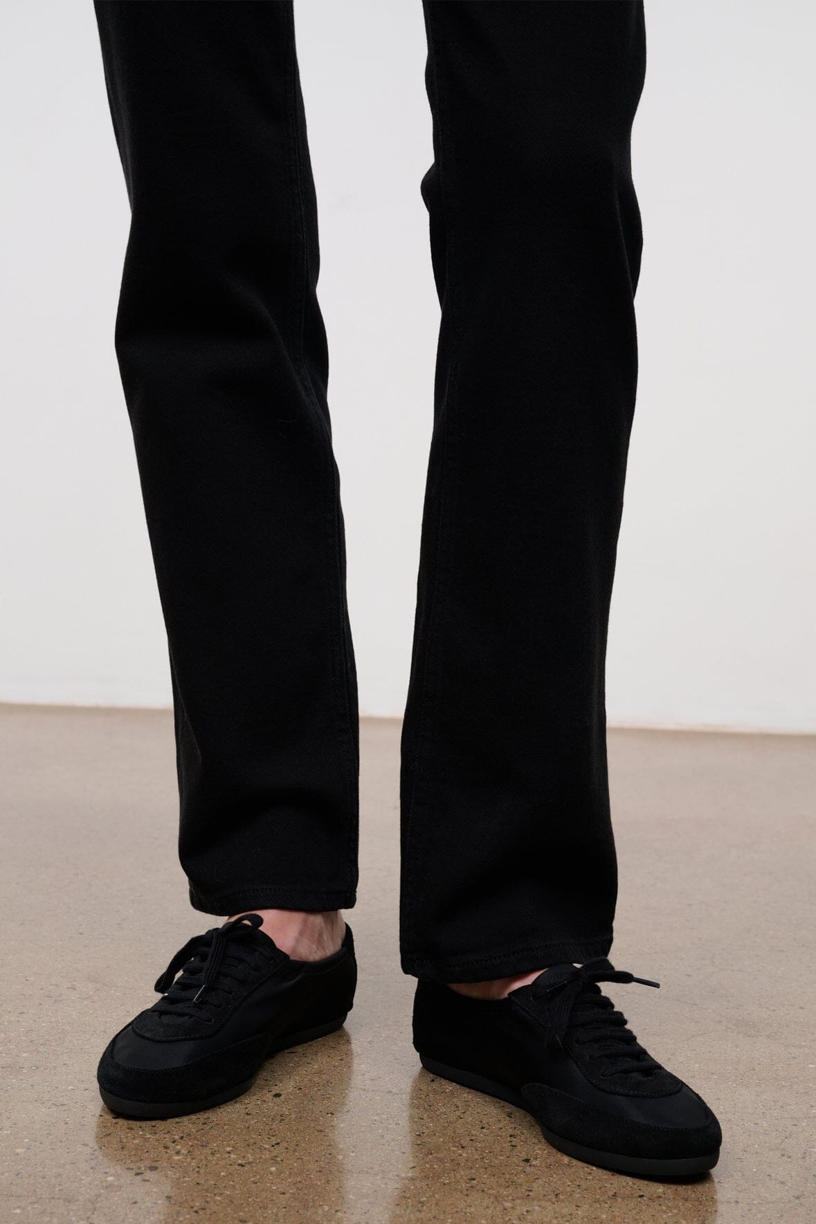 Black straight-fit jeans with button fly, belt loops, and ankle-length cuffs