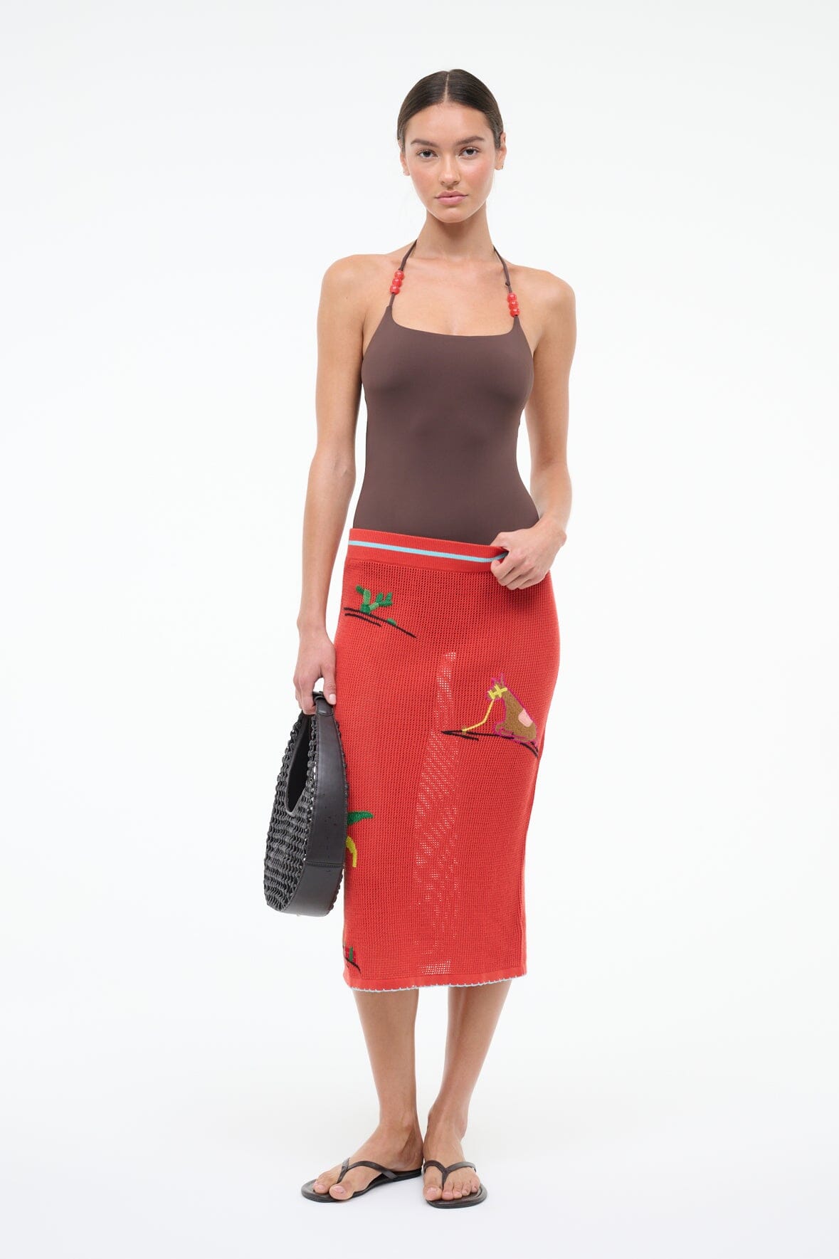 Dark brown halter one-piece with red beaded straps, worn with red skirt