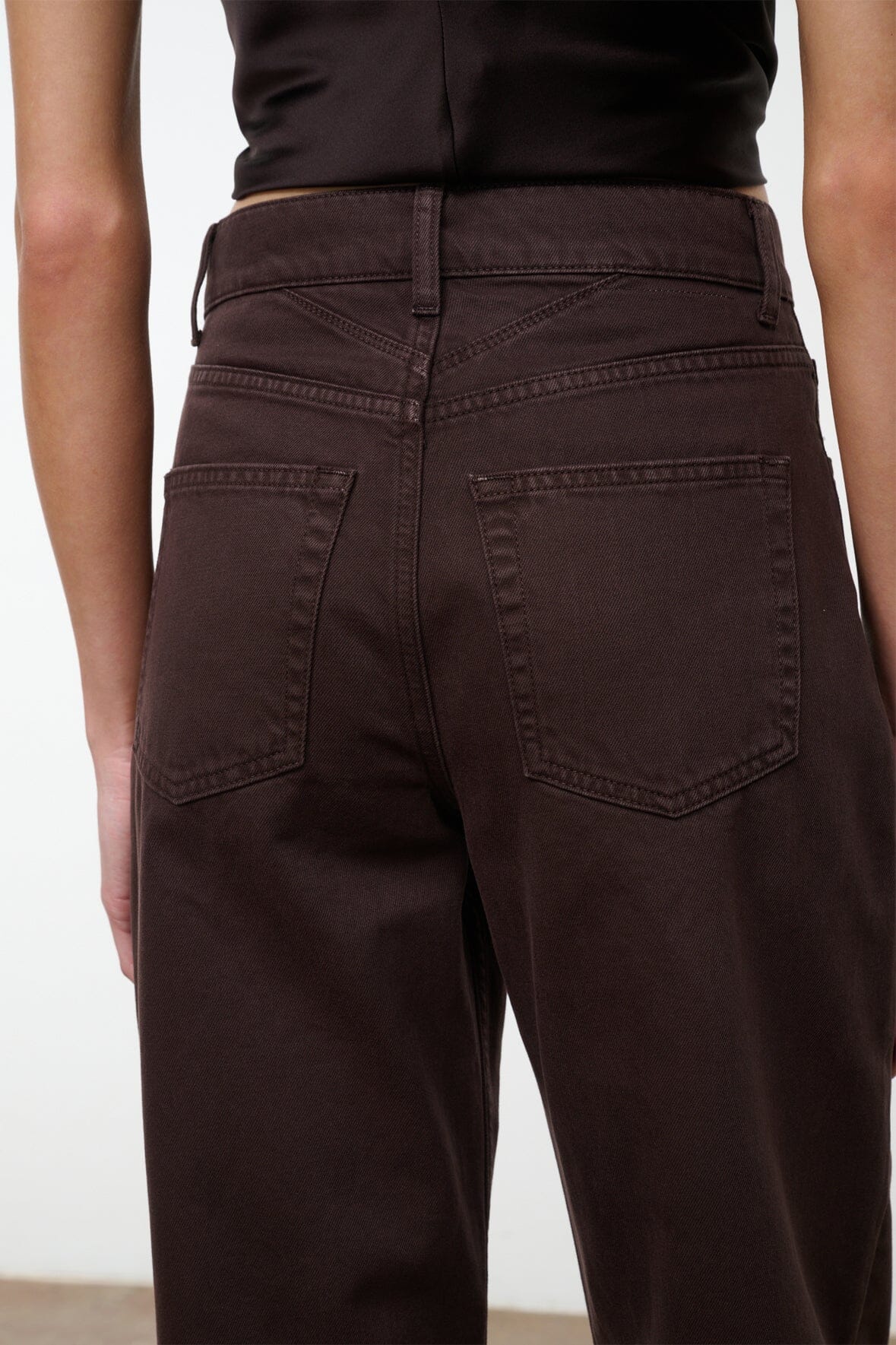 High-rise dark brown jeans with front button fly and belt loops