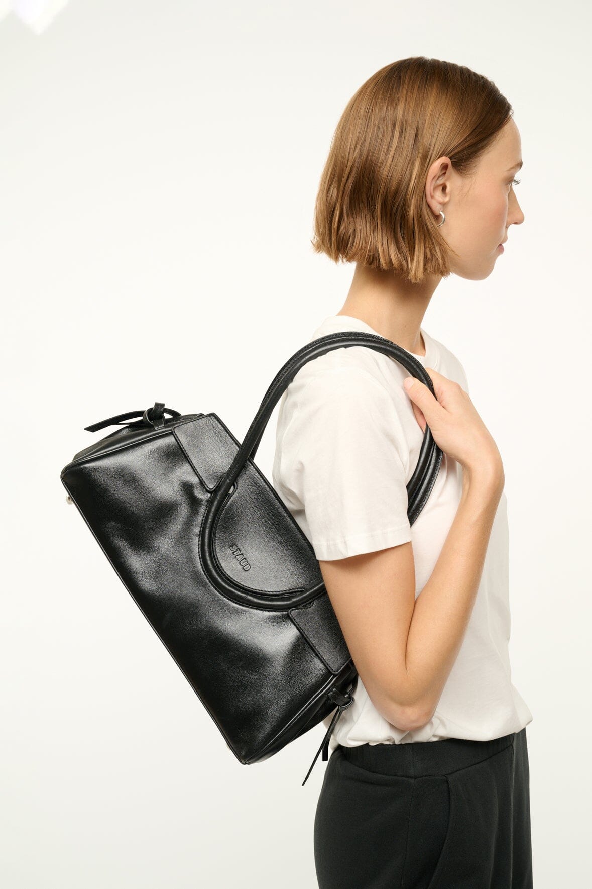 Black shoulder bag with top handles and drawstring tassel detail