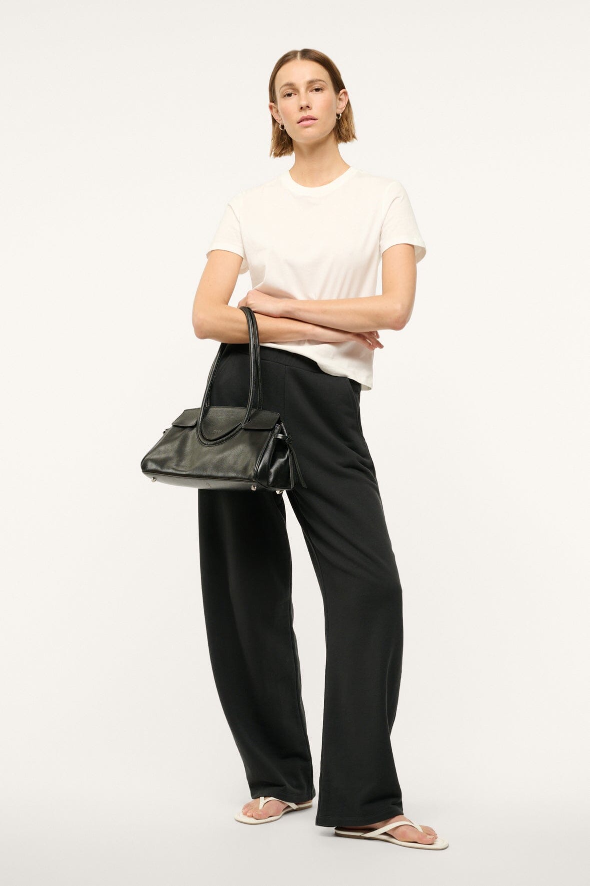 Black shoulder bag carried cross-body with short curved top handles